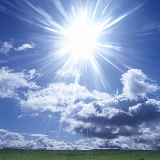 Bild von einem Sonnenhimmel mit ein paar Wolken über Wiese.