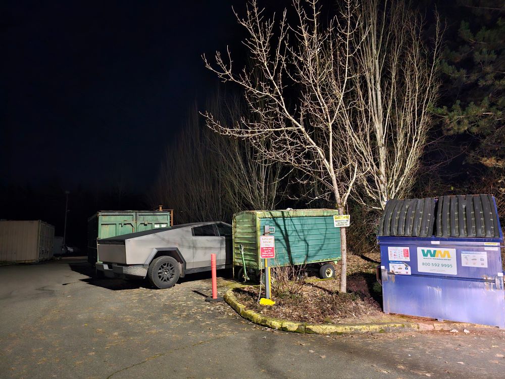 A cyber truck parked amongst trash bins 