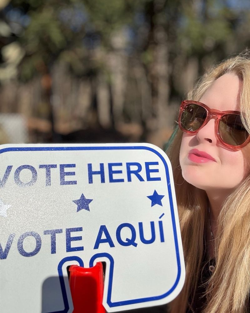 A selfie in front of a sign at my voting station that says “VOTE HERE VOTE AQUÍ.”