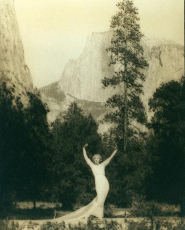Ruth St. Denis strikes a pose while wearing a long elegant white gown, outdoors in Yosemite Valley