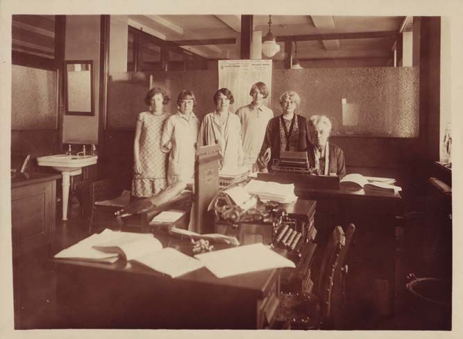 Group photograph of office staff members at the Fasken law firm, six women of various ages in an old fashioned office building behind desks with typewriters.
