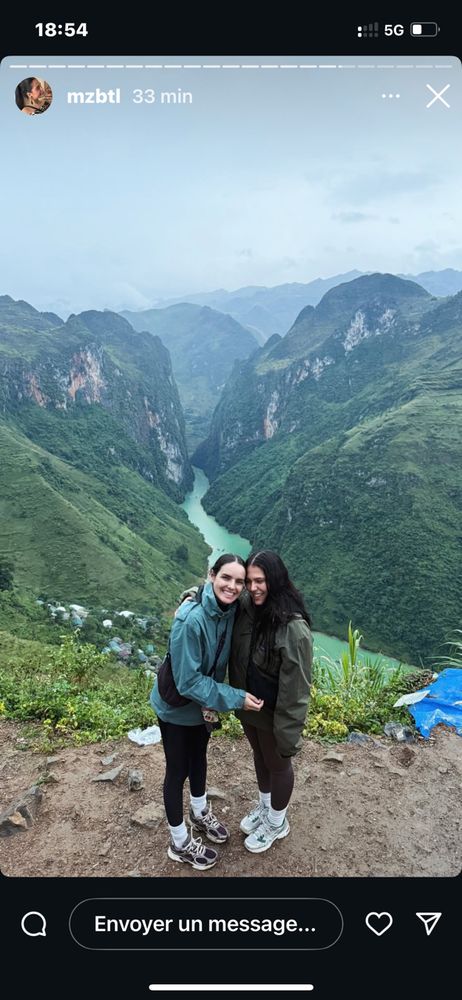 Deux jeunes filles en séjour d’agrément en terre presque du milieu .le paysage de montagnes douces encastre un fleuve qui reflète leur verdure. Les deux personnages en tenue de sport sourient grandement et envoient du love ; notamment à Kitty .Elles irradient de joie 🌹💗