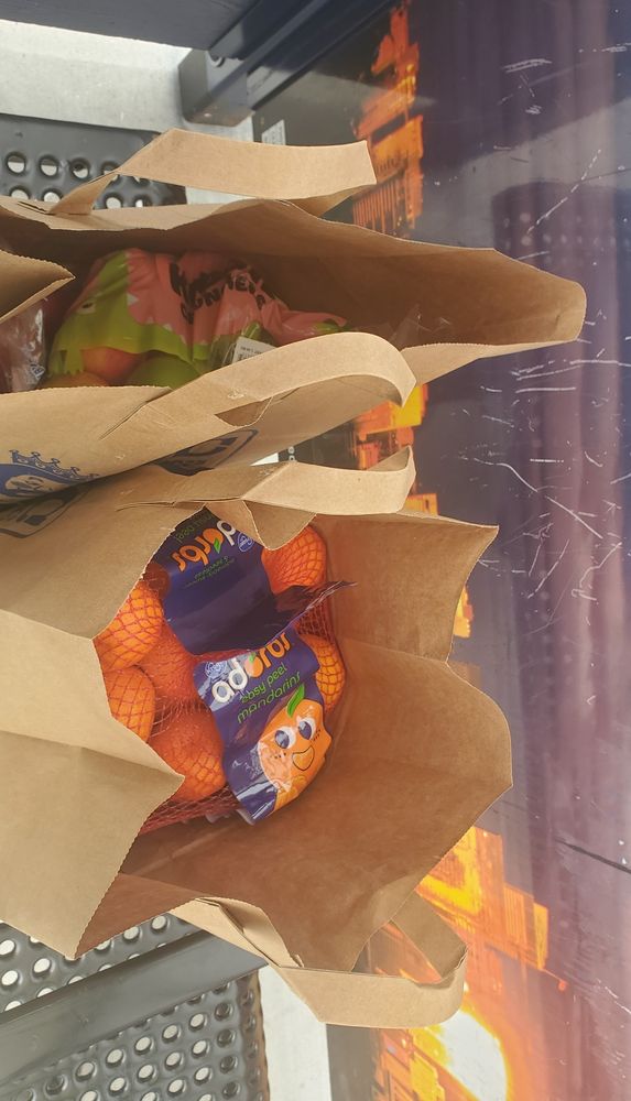 A grocery bag of apples and a grocery bag of clementines. 