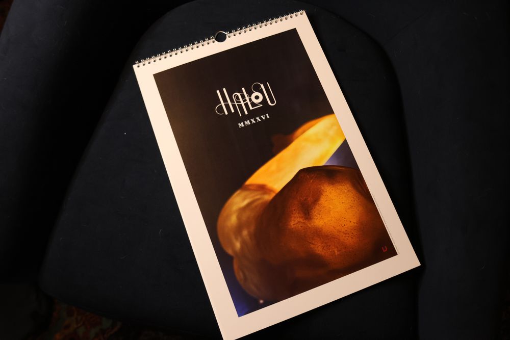 a large cardstock wall calendar with a spiral wire with the name Halou in fancy script