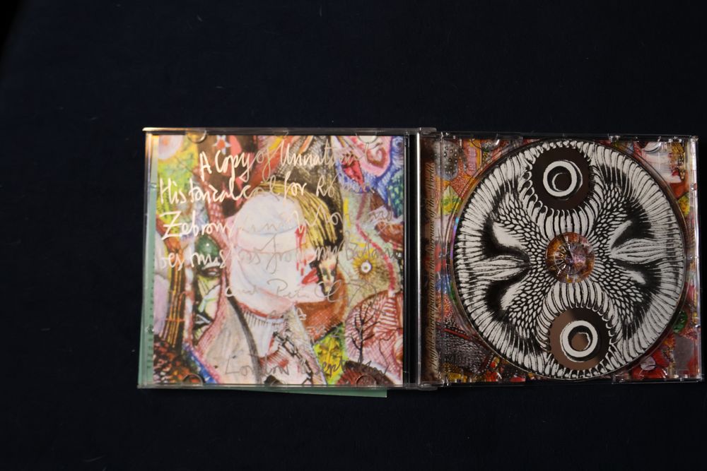 The cd case open to reveal an inscription on the booklet that's hard to read