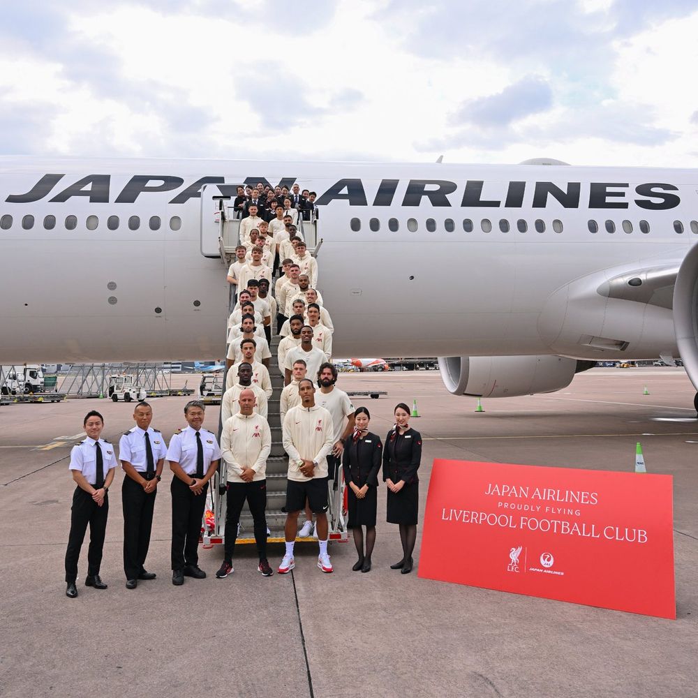 A photo of the squad alongside Japan Airlines crew on the steps of the aircraft, will a sign saying Japan Airlines proudly flying Liverpool Football Club.