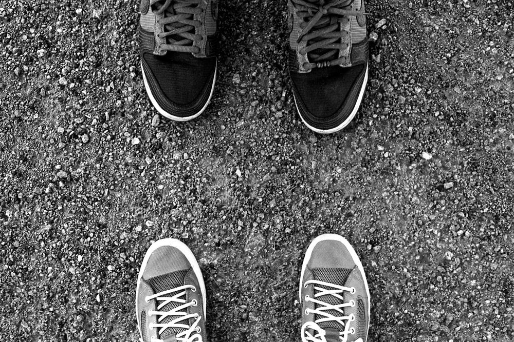 A black and white photograph of two people’s shoes poking in from the top and the bottom of the frame. 