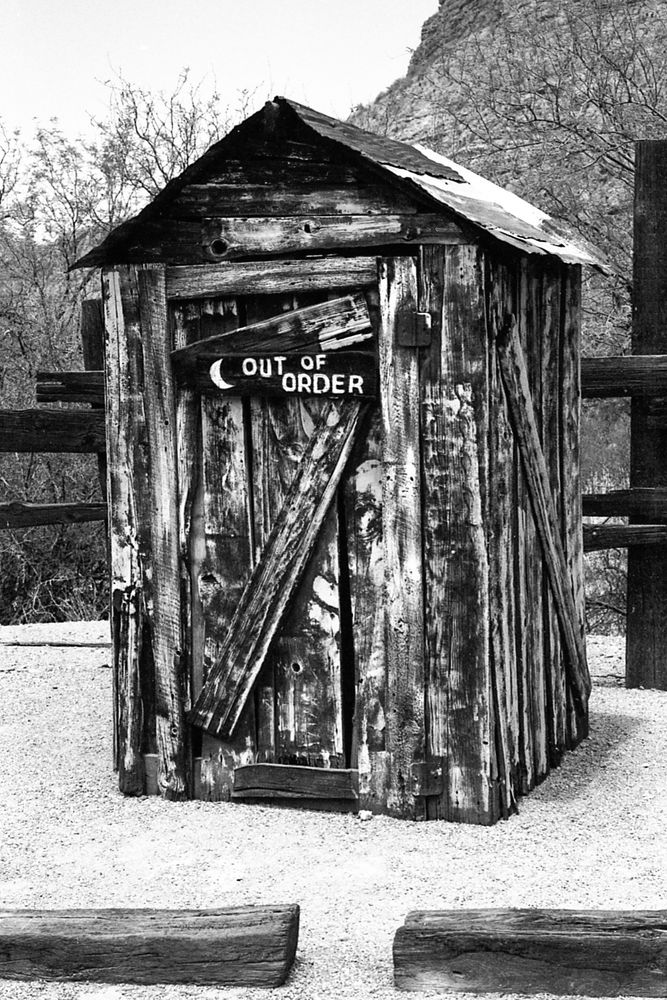 A wooden outhouse (assumed to be fake) with an “out of order” sign on the door. A cute piece of history located in Tortilla Flat, AZ. 