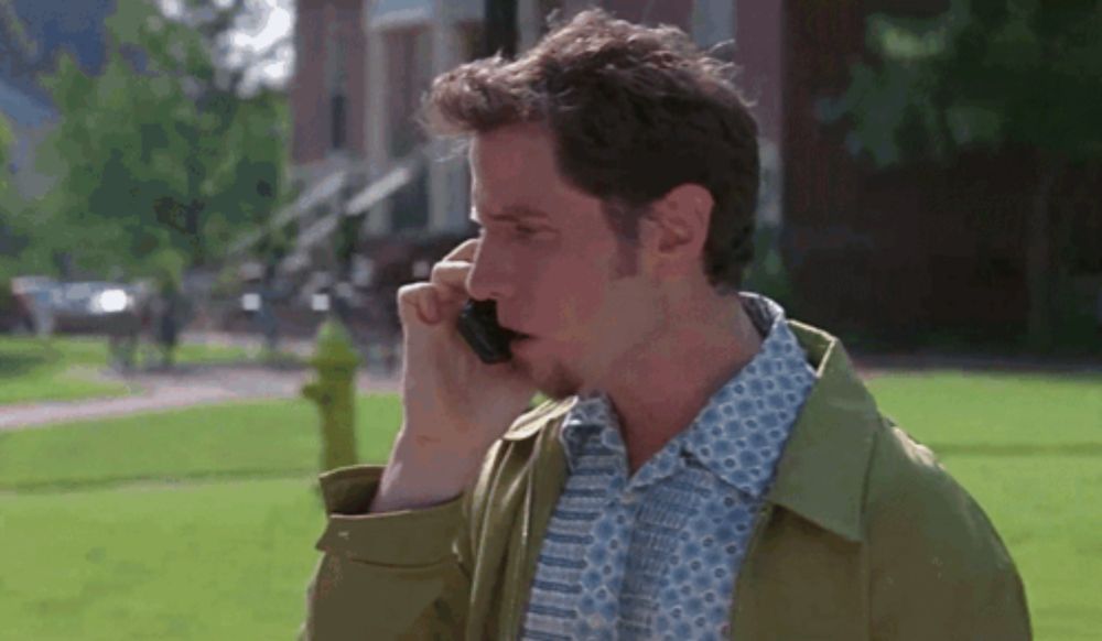 a man in a green jacket is talking on his cell phone