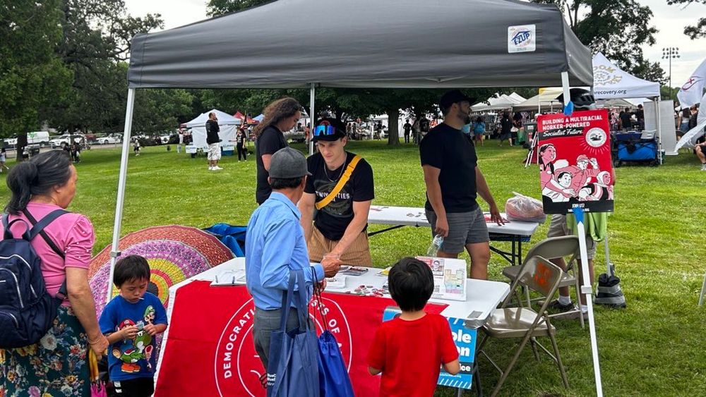 Picture of TCDSA volunteers with a family visiting the table