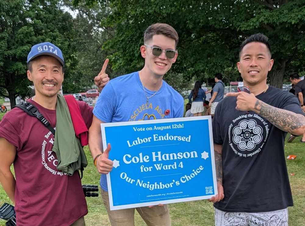 Cole Hanson holding his yard sign with two other people
