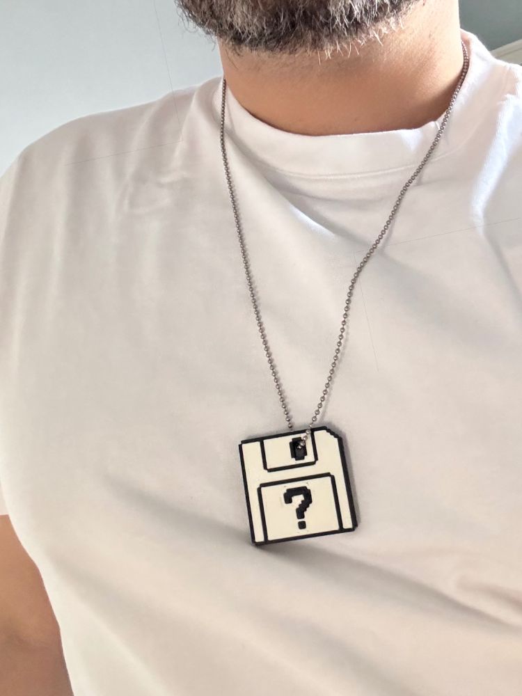 A man wearing a Macintosh startup disk question mark icon as a pendant on a chain.