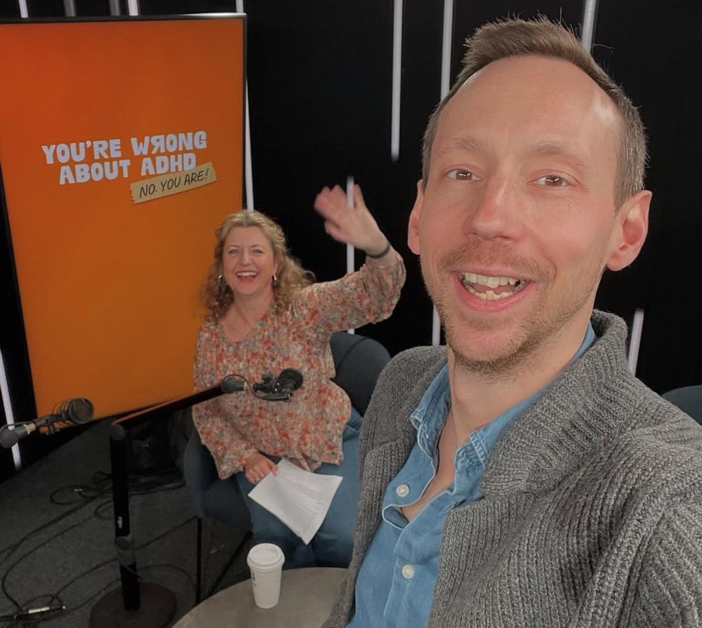 A photo of Sam Pittis and Katie Breathwick from You’re Wrong About ADHD, grinning in the studio after a recording session for their podcast. 