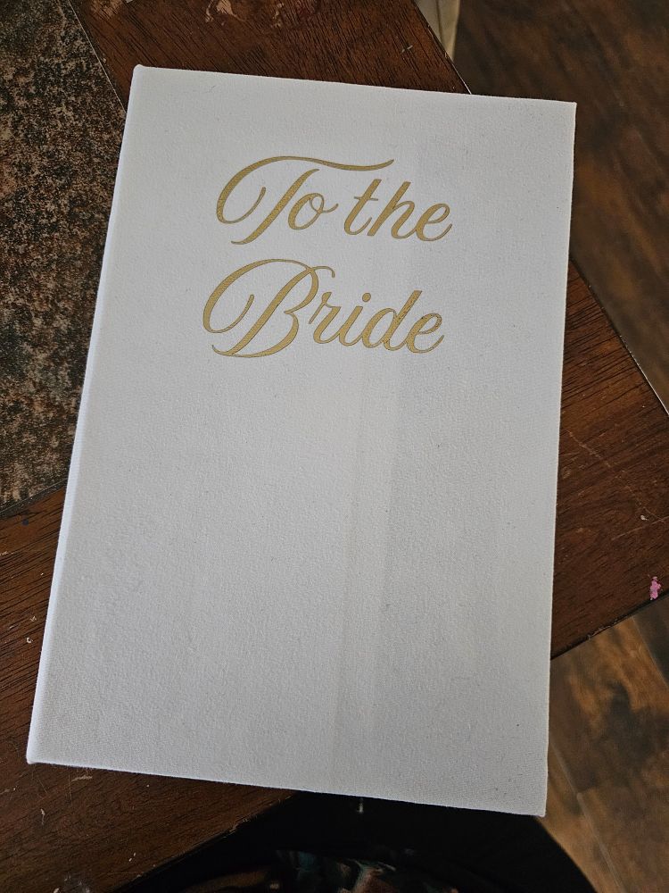 A direct shot of the newly bound cookbook with a clean white cover and the title in gold script.