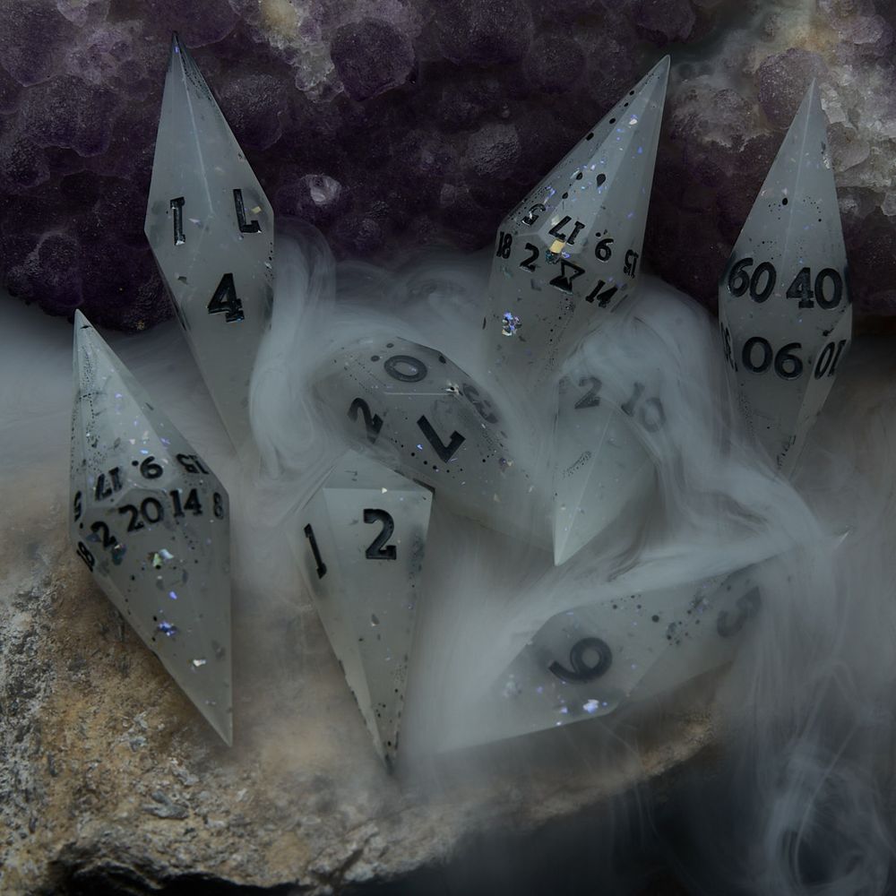 A misty colored crystal shaped dice set with holographic flakes and dark gray numbers sits on an amethyst geode with mist flowing over and around the dice.