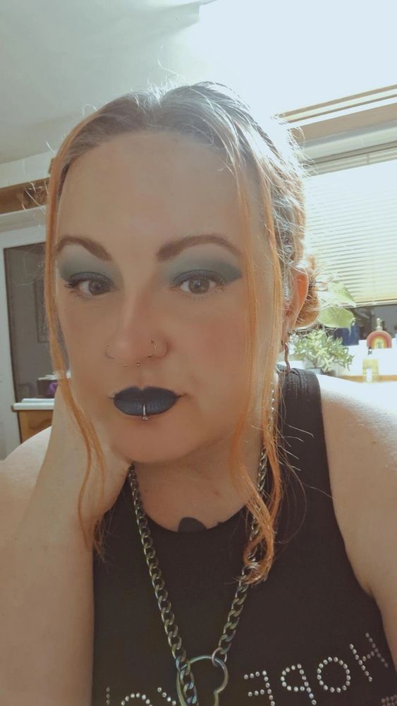 Phe with make up and hair in buns and a slip chain choker