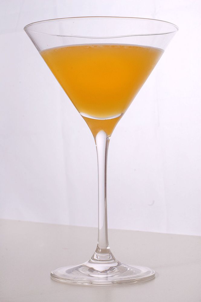 A cloudy orange drink in a martini glass