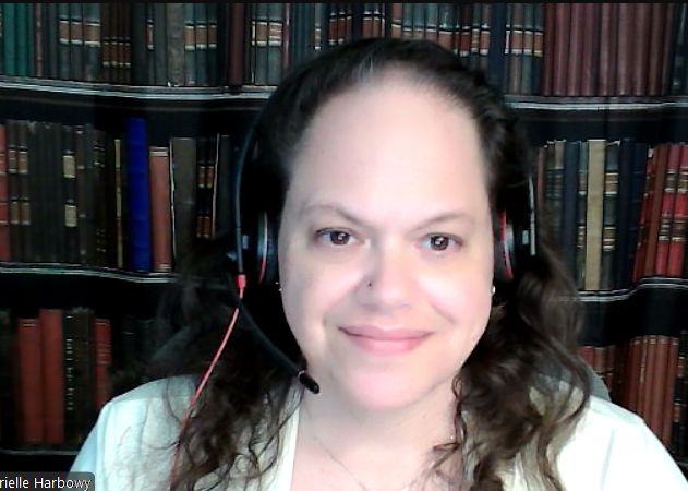 A 53-year-old white woman with brown hair, wearing headphones, in front of a backdrop that looks like a bookcase.