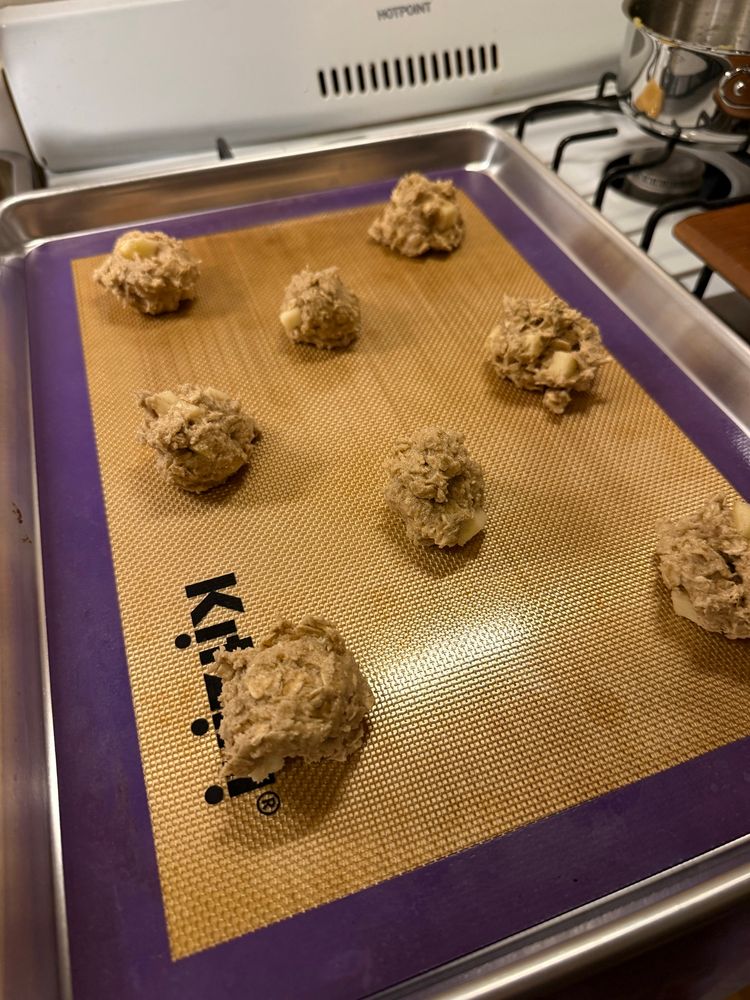 Apple cinnamon oatmeal cookies spaced out on a baking pan