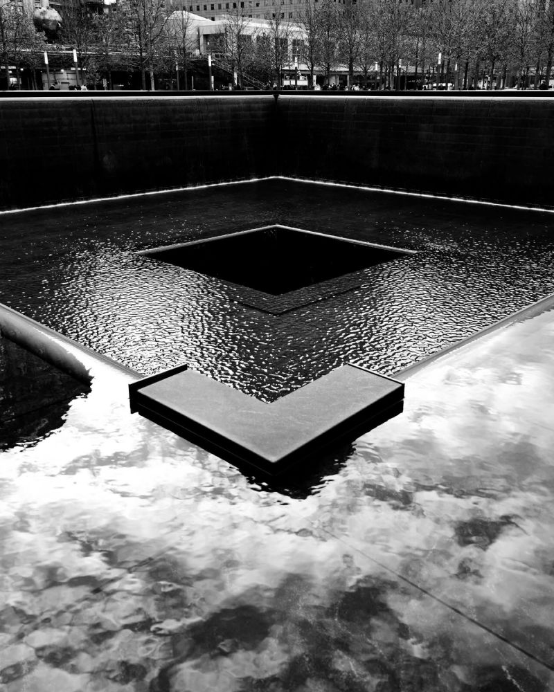 Picture looking into the World Trade Centre waterfall in monochrome with reflections of the clouds above