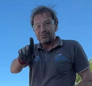 A bitter man looking bitter pointing to a better human than him, wearing saftey glasses while he destroys a village amenity, with a lovely blue sky behind.