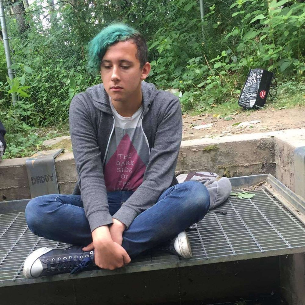 Nish Bae pre-transition with blue hair and a dark side of the moon shirt
