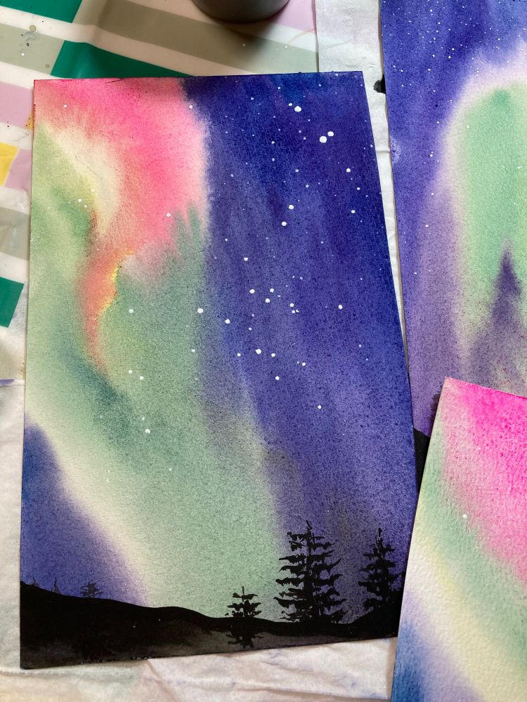 Watercolour painting of aurora with little dots of stars & silhouettes of trees