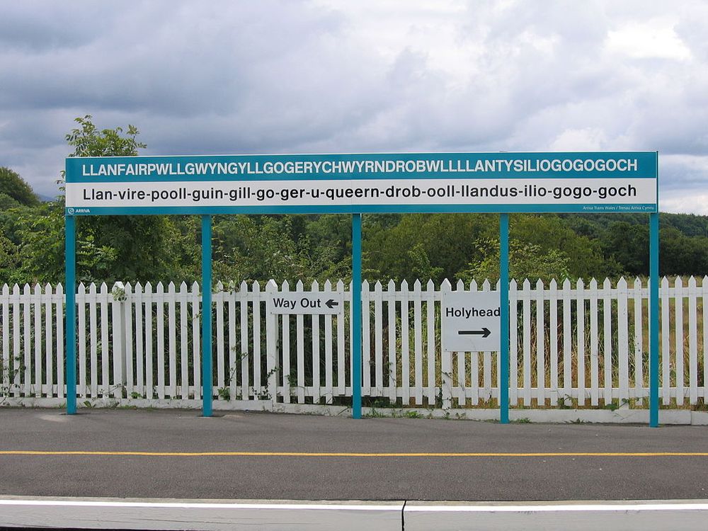 Sign at a Train Station with the name of the community named "Llanfair­pwllgwyngyll­gogery­chwyrn­drobwll­llan­tysilio­gogo­goch" on it.
