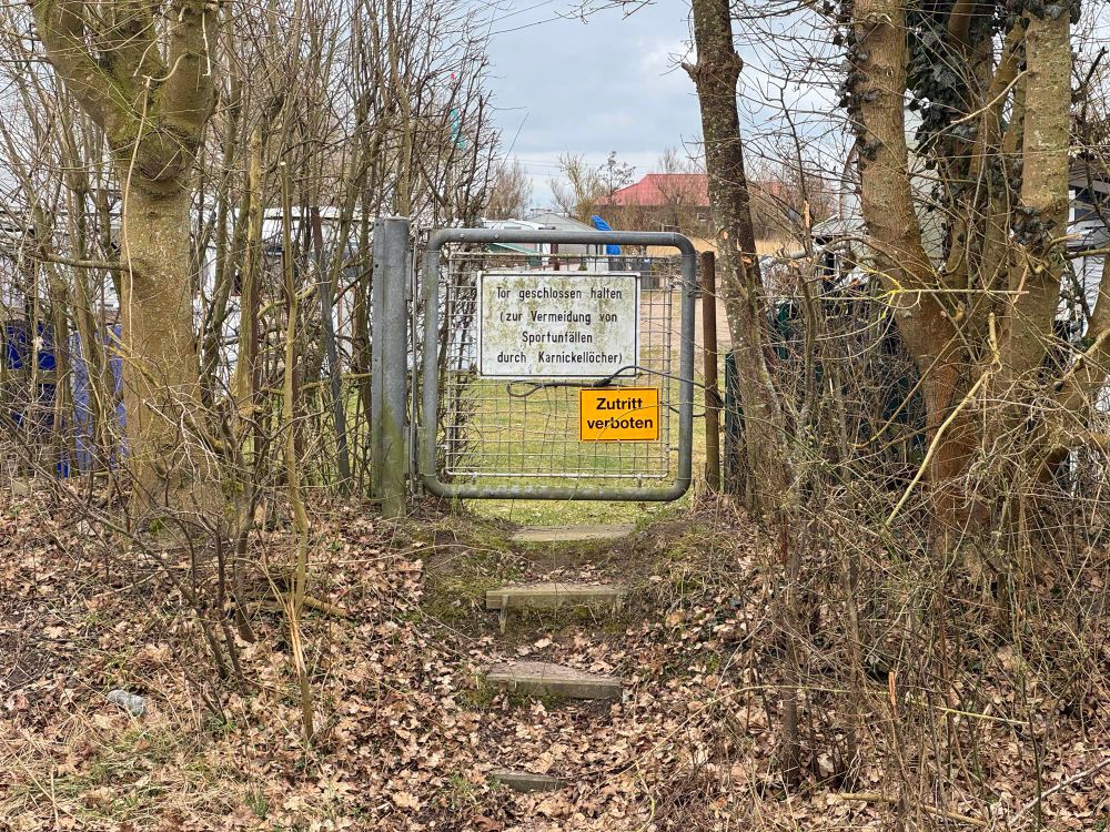 Schild auf einem Tor zu einem Kleingarten mit dem Text:

Tor geschlossen halten (Zur Vermeidung von Sportunfällen durch Karnickellöcher!)