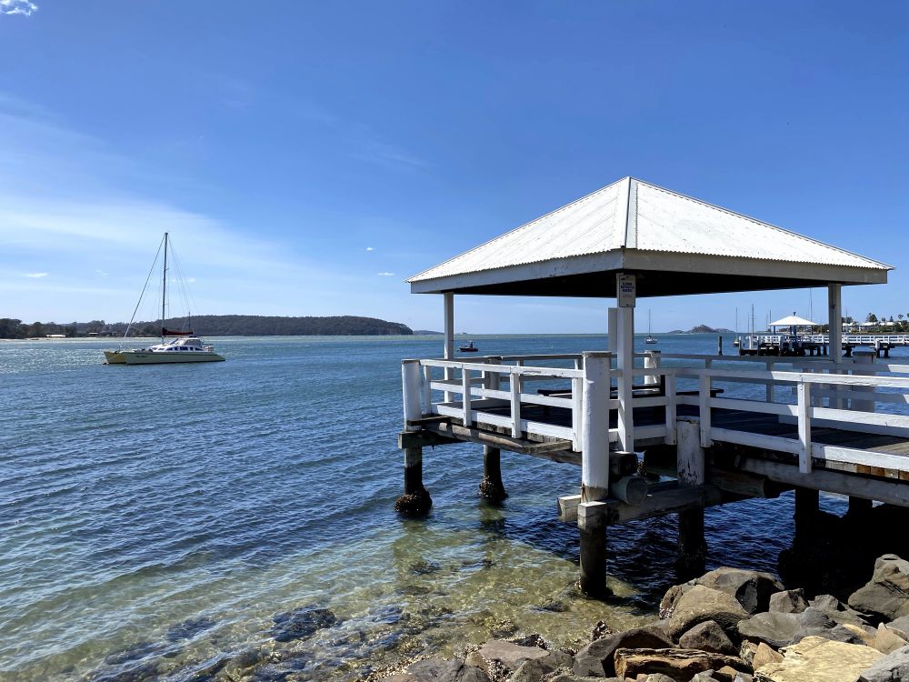 Batemans Bay with sailboat and jetty, clear blue water