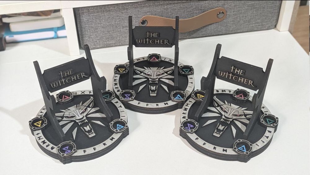 Foto de tres soportes para teléfono móvil o mando de consola inspirados en The Witcher