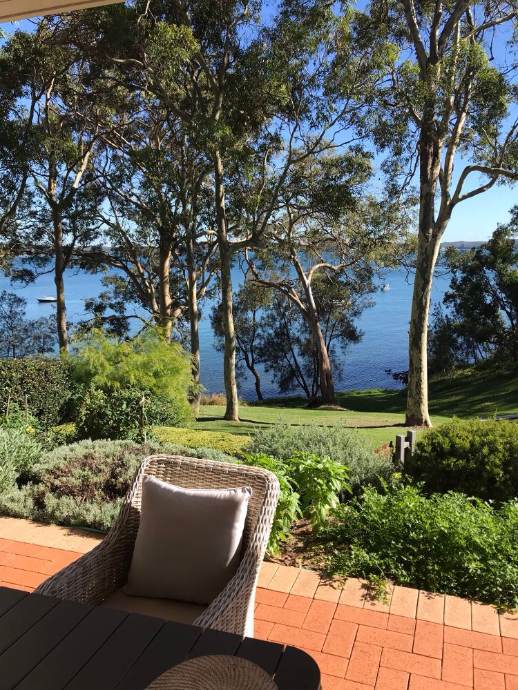 Outdoor patio with grass leading down to lake view 