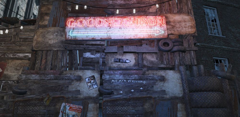 Shot from Fallout 4. Outside the border wall of Goodneighbor. A sign is built into the improvised wall pointing the way to the entrance. Underneath the sign on one of the boards, written in chalk are the words, "ALL ARE WELCOME"