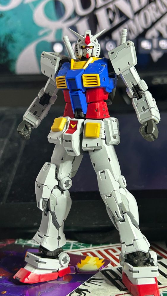 The classic Gundam standing with its legs wider than shoulder-length and arms pulled back, looking at the camera.