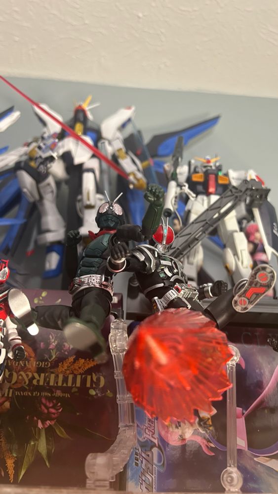 Front view of Shin Kamen Rider 01 and Kamen Rider Faiz performing a double rider kick towards the camera