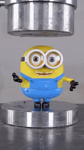 a toy minion is being pressed under a metal cylinder