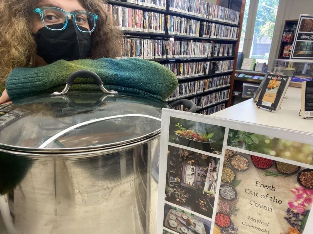 Woman posing with a canning pot next to a flyer that says Fresh out of the Coven.