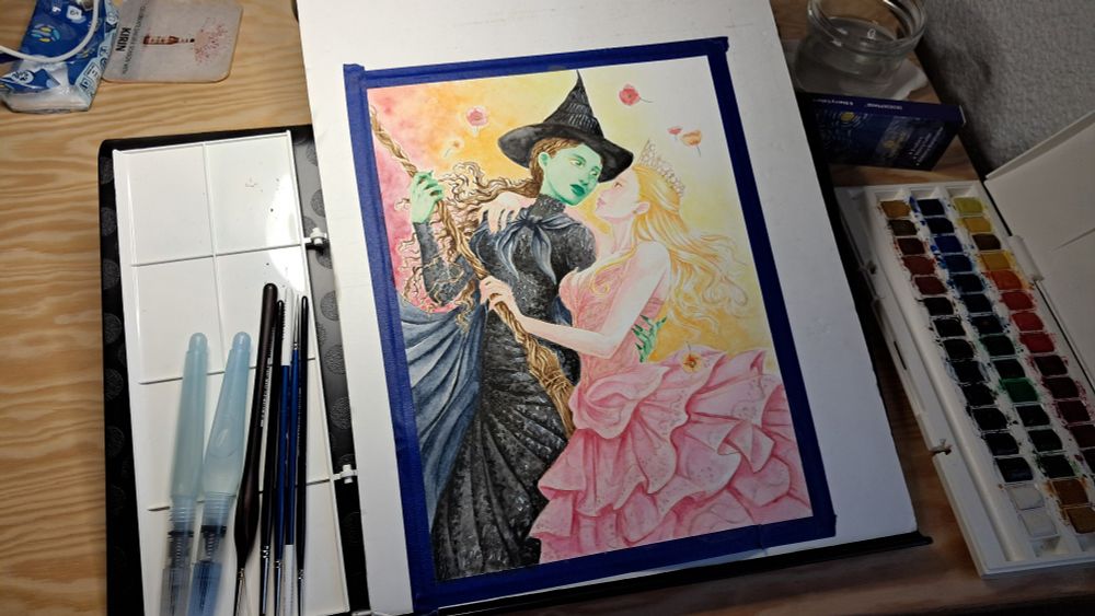 Una foto de la pintura en proceso, con los materiales empleados: distintos pinceles y una paleta de acuarelas. 

A photo of the painting still in progress, with the materials used: different brushes and a watercolor palette.