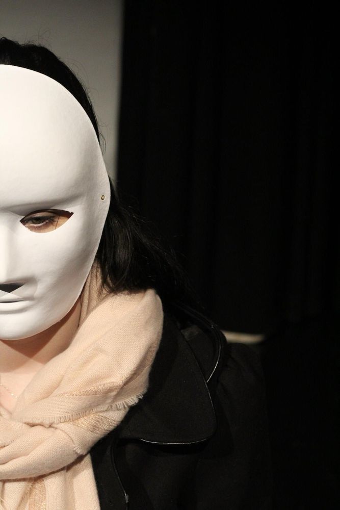 A woman is wearing a white full face mask. 