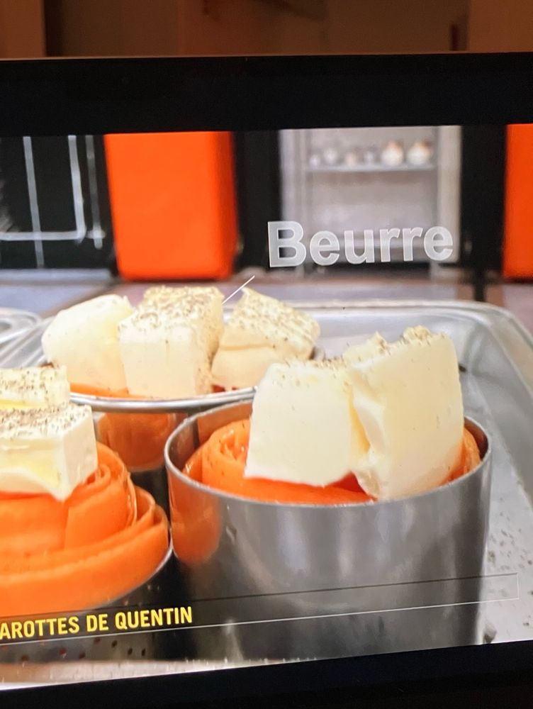 Some carrot flowers with a huge amount of butter on top, with the word “beurre” on the screen. 