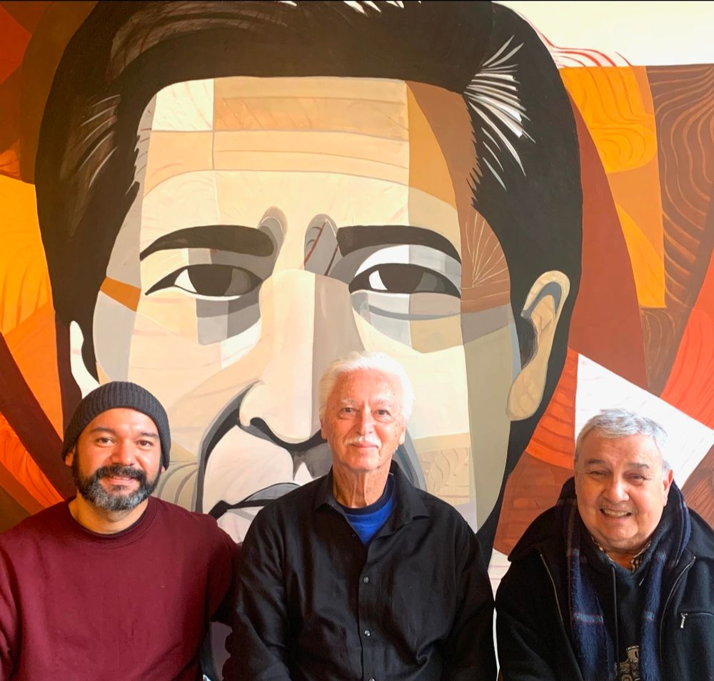 Four men sitting in front of a mural