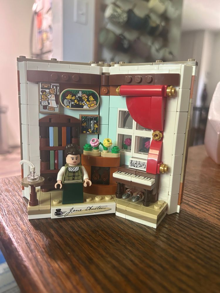 Lego Jane Austen featuring a writing desk, fireplace, piano, and bookshelf