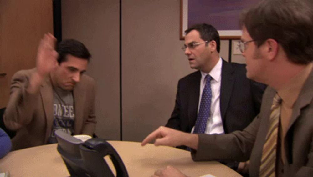 three men are sitting around a table with one wearing a shirt that says duke on it