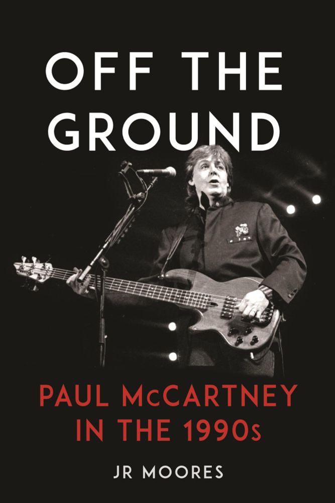 The front cover of JR Moores, Off The Ground: Paul McCartney in the 1990s. Illustrated by a black and white photo of Macca with a guitar singing his little heart out circa 1990-something. 