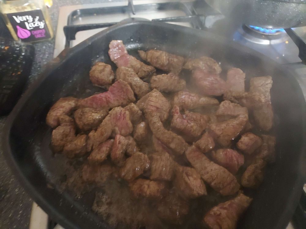 Slices of rump steak, coated in black and white pepper with  a hint of salt an hour beforehand. Sizzling in sesame oil with some soy sauce.