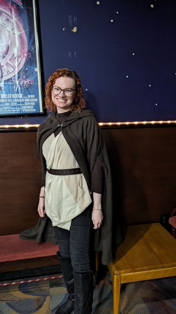Kimberly smiling in a movie theater lobby, wearing a brown cloak and a Jedi costume.