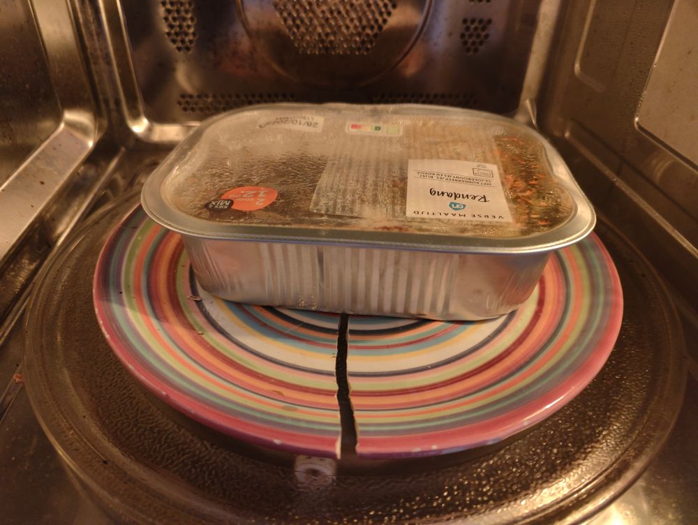 Foto van de met de magnetron opgewarmde rendangmaaltijd. Het bord eronder, dat al honderden keren in deze magnetron is gebruikt, is geknapt.