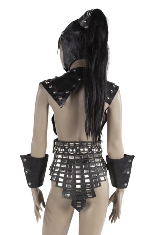 Back photo of "A screen-matched silver-tone studded leather costume worn by Cassandra Peterson as Big Mama in the Tim Burton directed film Pee-Wee's Big Adventure (Warner Bros., 1985). Peterson (not wearing her Elvira costume) wears the vest portion of the costume when tormenting Pee-Wee at a biker bar. Elvira first wore the costume at her 1983 Knott's Berry Farm Show. The costume also includes wrist cuffs and a head dress with a black ponytail hairpiece from that performance, not worn in the film. A photograph from one of these performances was published in the coffee table book Elvira: Mistress of the Dark (California: Tweeterhead Publishing, 2016). No size tag."   source -https://www.juliensauctions.com/en/items/67965/elvira-biker-mama-screen-matched-silver-tone-studded-leather-costume-from-pee-wee-s-big-adventure-wi