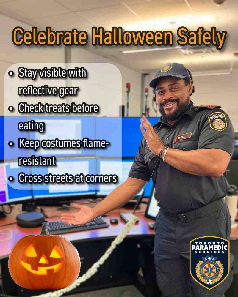 Emergency Medical Dispatcher standing in front of a desk gesturing toward Halloween safety tips. Text reads: "Celebrate Halloween Safely. Stay visible with reflective gear. Check treats before eating. Keep costumes flame-resistant. Cross streets at corners."