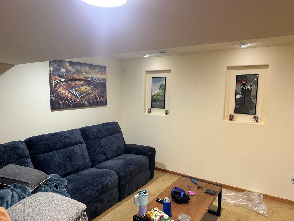 A canvas print of Highmark Stadium hung above a blue couch in a cool basement.